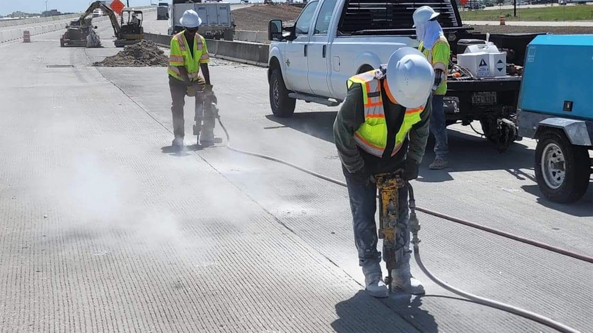 Workers using pneumatic hammer drills on roadway