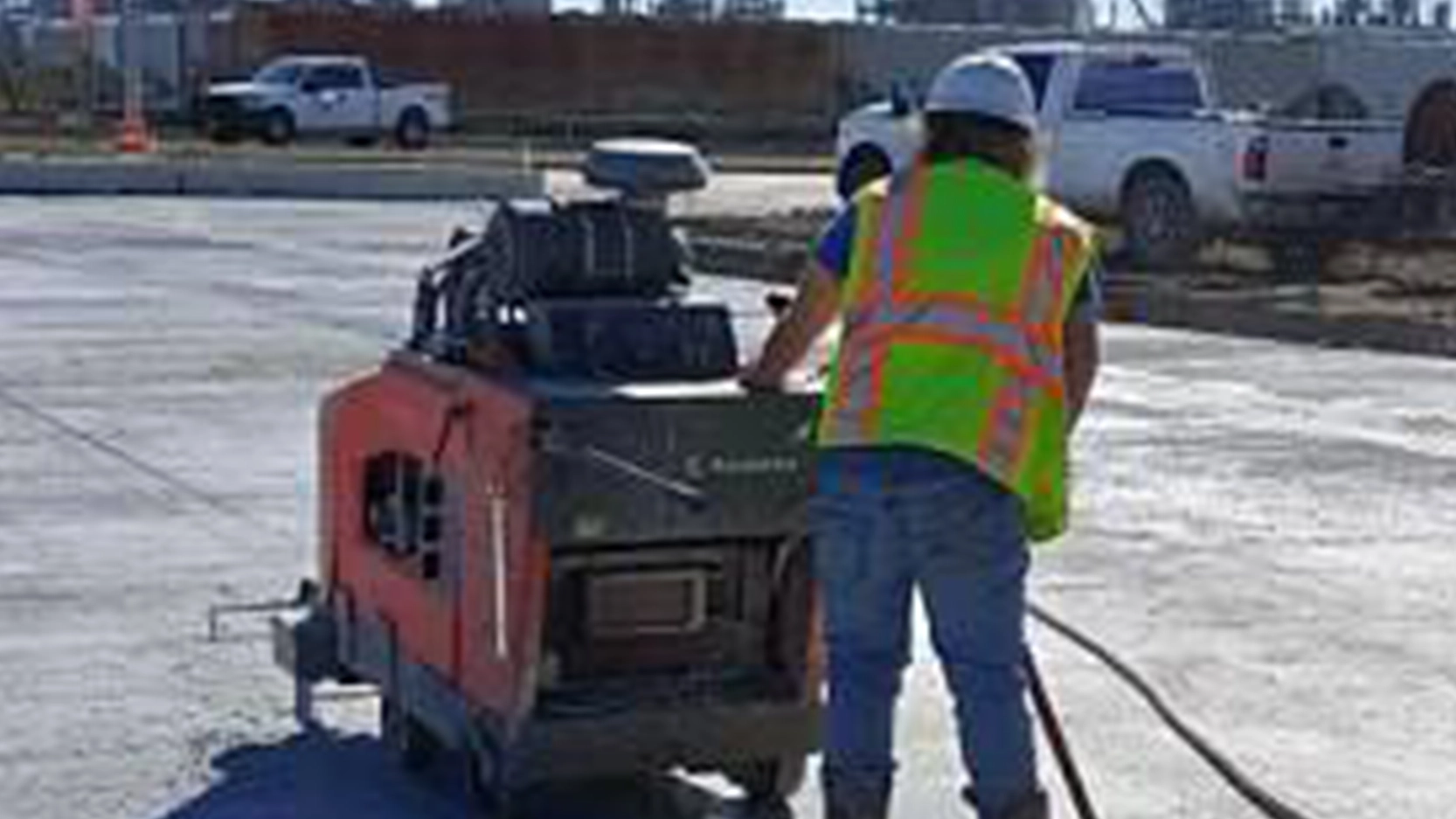 Workman sawing concrete with machine