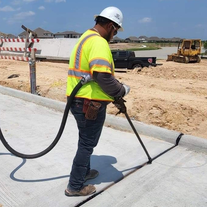 Worker injecting sealing material in expansion joint