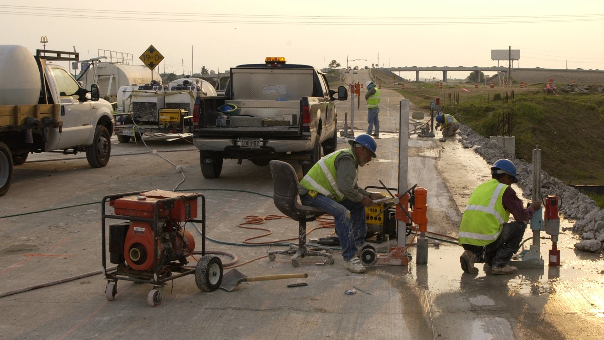 Workers drilling concrete cores on closed roadway