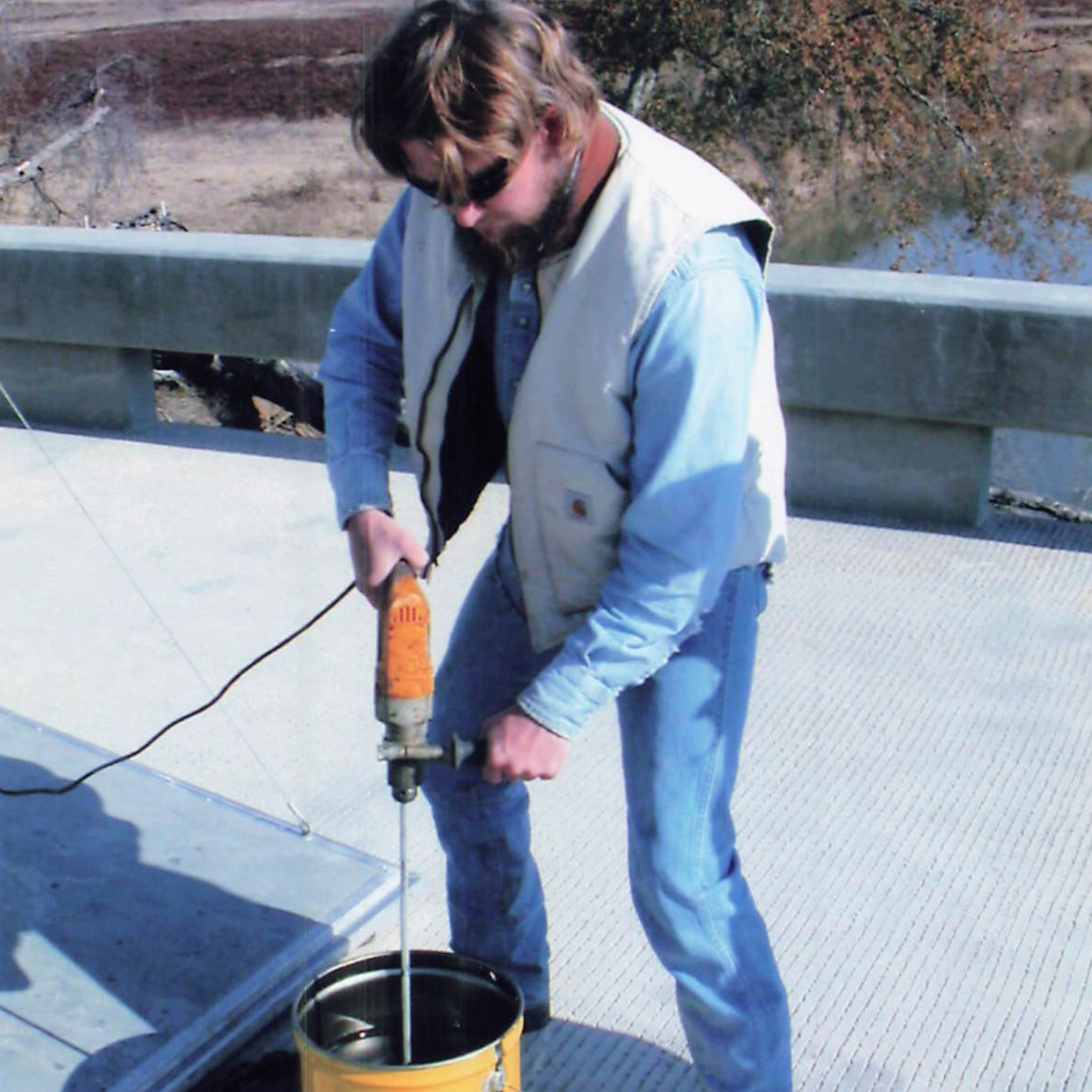closeup of worker mixing epoxy in pail