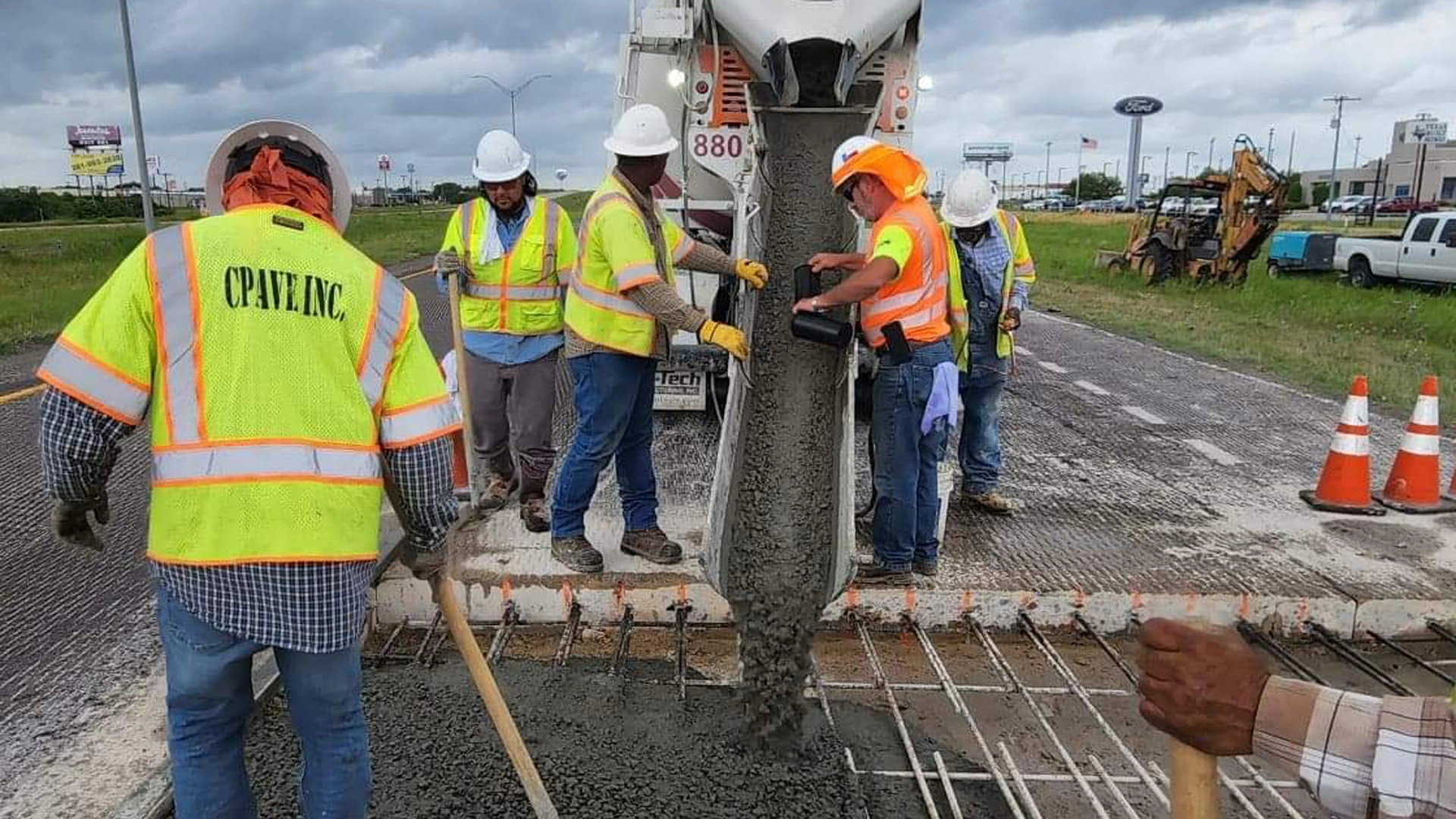 Workers with concrete being poured for roadway repair