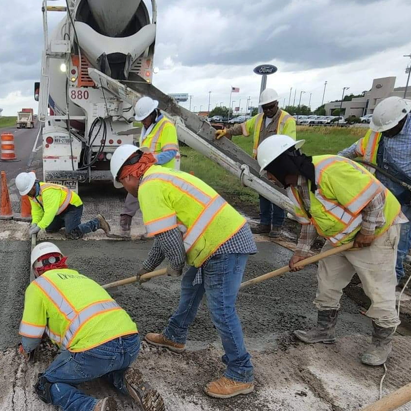 Workers spreading concrete on roadway repair