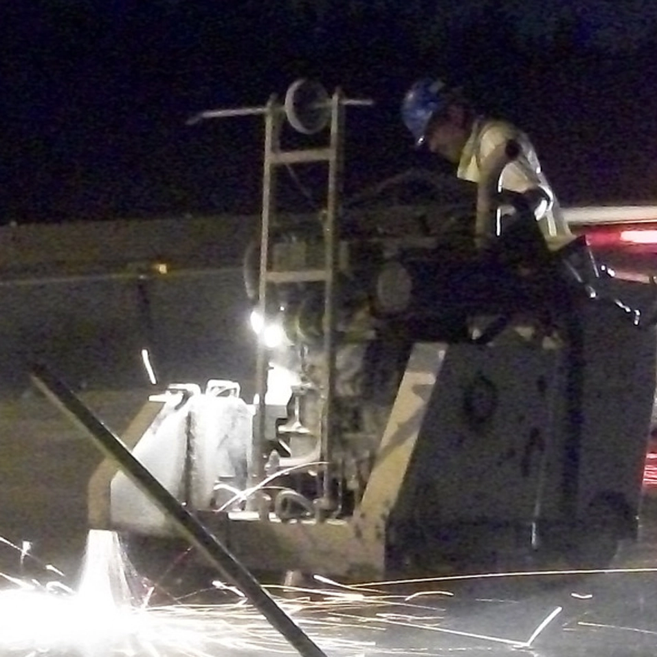 Worker sawing concrete at night with sparking machine