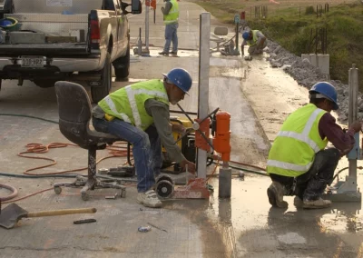 Workers seated and kneeling while drilling cores in concrete