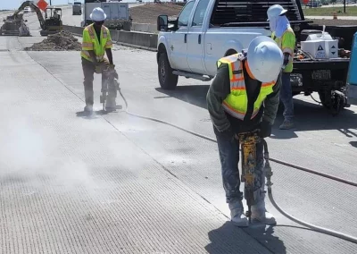 Workers using pneumatic hammer drills on roadway