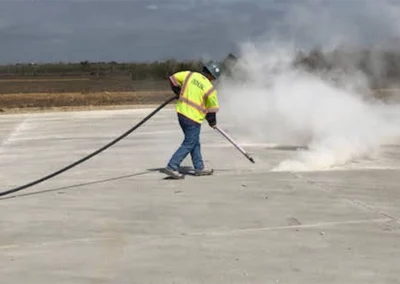 Worker blowing out concrete joint with compressed air