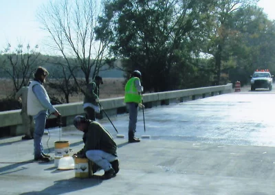 Workers spreading epoxy on bridge surface