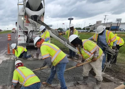 Workmen spreading concrete for road repair
