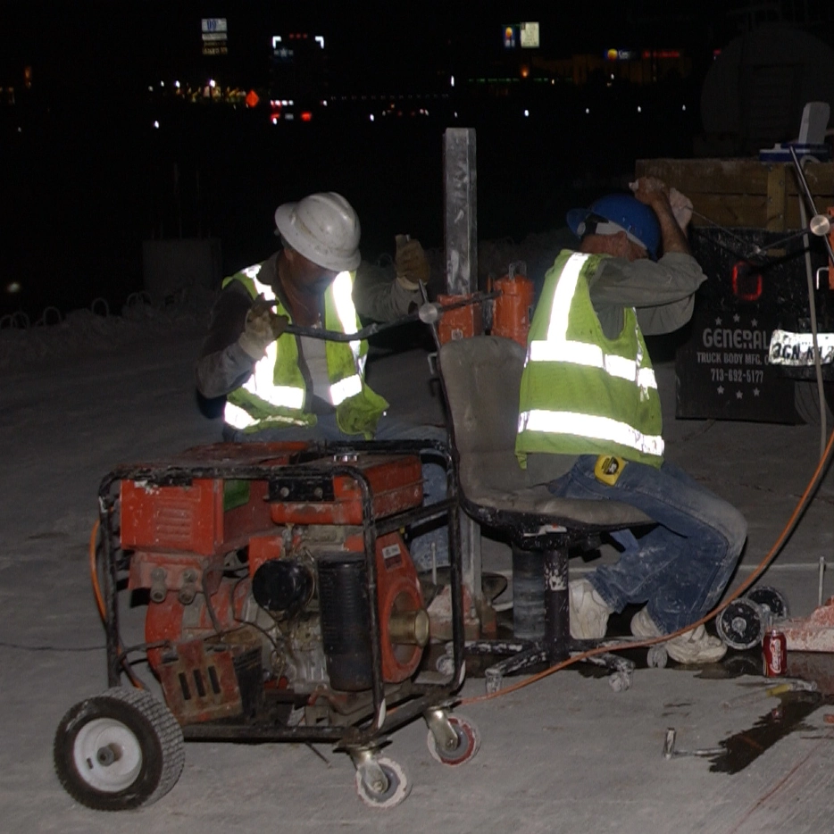 Workers seated while drilling cores in concrete at night